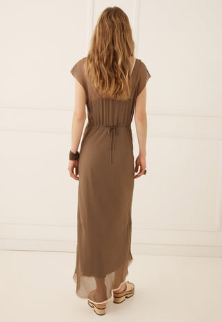 a-woman-viewed-from-behind-wearing-a-brown-midi-dress-with-short-cap-sleeves-a-gathered-waist-and-a-drawstring-tie-paired-with-platform-sandals-against-a-white-paneled-wall